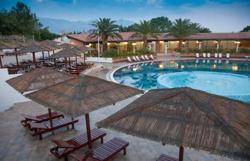 a pool with chairs and umbrellas next to a resort at Hotel Slovenska Plaža in Budva