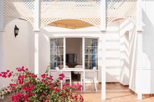 un patio con mesa, sillas y flores en Apartamentos LIVVO Coloradamar en Playa Blanca