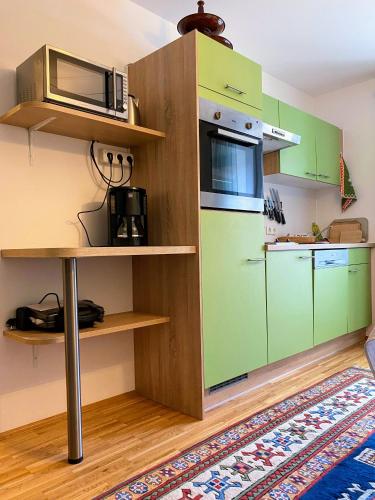 a kitchen with green cabinets and a microwave at Obersdorfer Hof in Bad Mitterndorf