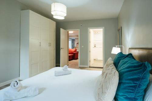 a bedroom with a large white bed with blue pillows at The Zentral Suites & Apartments in Seville