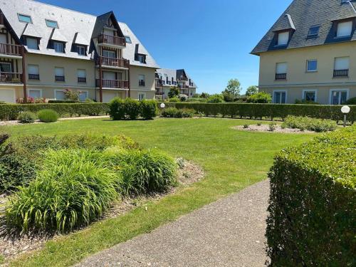 un parc en face d'un bâtiment avec pelouse et buissons dans l'établissement Le Jardin de Blonville - À 10 min à pied de la plage - tennis & équitation à côté, à Blonville-sur-Mer