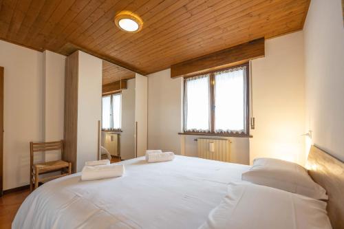 ein großes weißes Bett in einem Zimmer mit zwei Fenstern in der Unterkunft Cesa Alpes 2 in Campitello di Fassa
