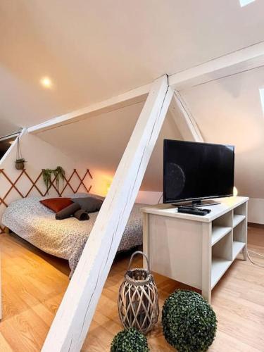 Cette chambre comprend un lit et un bureau avec une télévision. dans l'établissement Petit Loft Centre Ville Historique proche GARE TGV, à Mulhouse