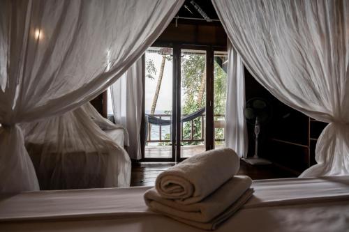 a bedroom with a bed with towels and a window at Casa Nemo Beach Resort & Spa in Sabong