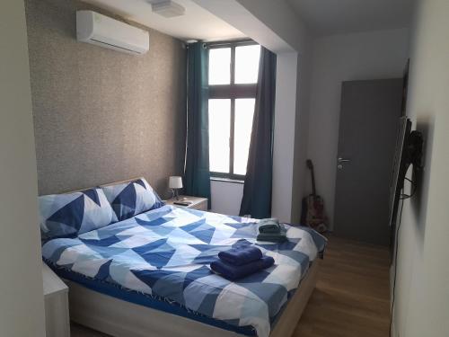 a bedroom with a blue and white bed with a window at Cosy 4 Bedroom Apt with use of Pool in St Paul's Bay