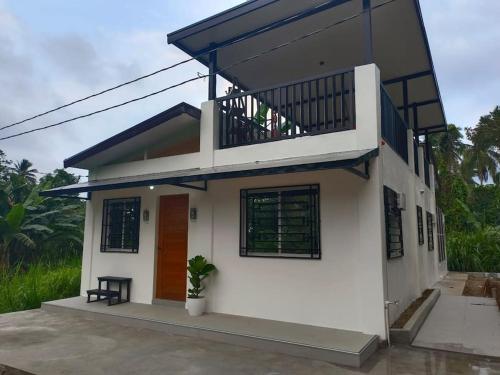 a small white house with a balcony at Charming House with Jacuzzi in Indang