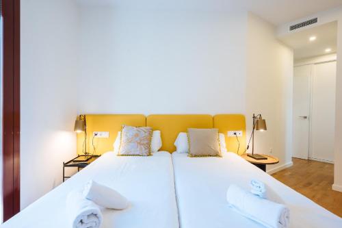 a bedroom with a large white bed with two pillows at The Zentral Suites & Apartments in Seville