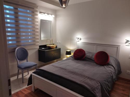 Un dormitorio con una cama con almohadas rojas y una silla en Appartement Luxe dans Villa Borghese La Boisse, en La Boisse