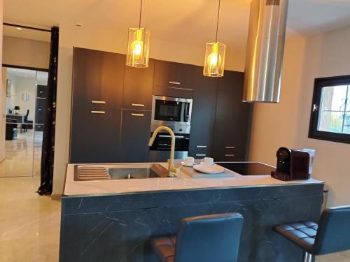 cocina con fregadero y barra con sillas en Appartement Luxe dans Villa Borghese La Boisse, en La Boisse