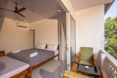 a bedroom with two beds and a chair on a balcony at Crystall Goa, Onyx Edition in Palolem