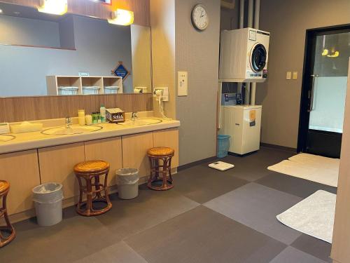 uma casa de banho com 2 lavatórios e 2 bancos em Hotel Route-Inn Akita Tsuchizaki em Akita