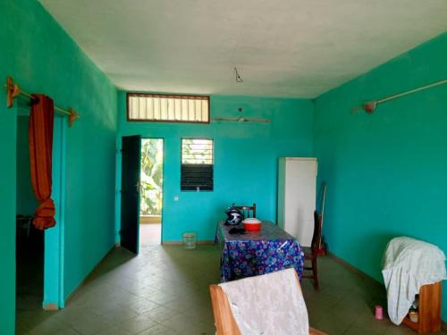 Zimmer mit einem Tisch und einer blauen Wand in der Unterkunft Appat'Adjanohoun in Ouidah