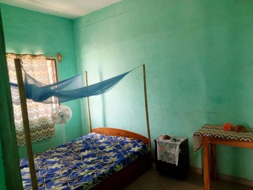 een slaapkamer met een bed en een blauwe muur bij Appat'Adjanohoun in Ouidah