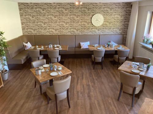 un restaurante con mesas y sillas de madera y una pared de ladrillo en Pension Orketal, en Medebach