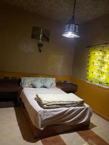 a bedroom with a bed in a room with a light at GITE Take your time in Merzouga