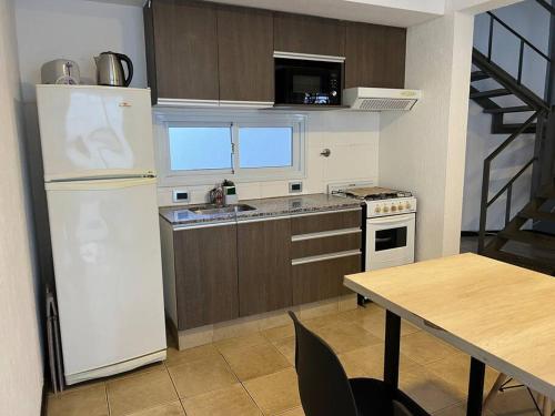 a kitchen with a white refrigerator and a table at Duplex hasta 5 personas en hermosa zona T3 in Guaymallen