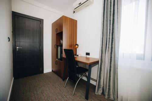 Habitación con escritorio, silla y puerta. en Garni Hotel Radović en Kragujevac