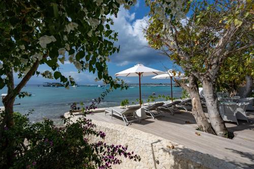 a beach with chairs and an umbrella and the ocean at White Horse Resort in Nusa Lembongan