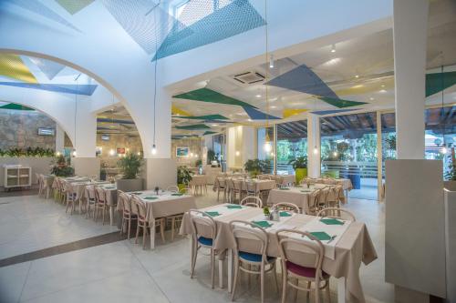 una sala da pranzo con tavoli e sedie bianchi di Hotel Slovenska Plaža Lux a Budua