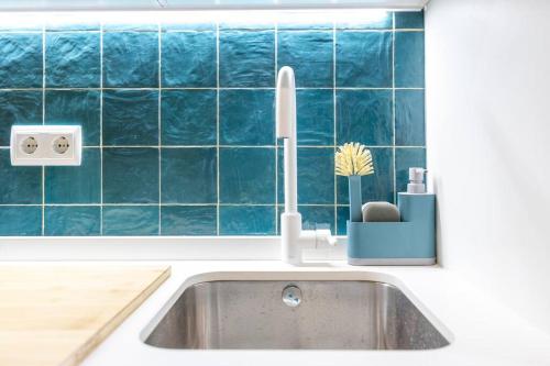 a sink in a kitchen with a blue tile wall at Estudio moderno y acogedor en Madrid Rio nº8 in Madrid