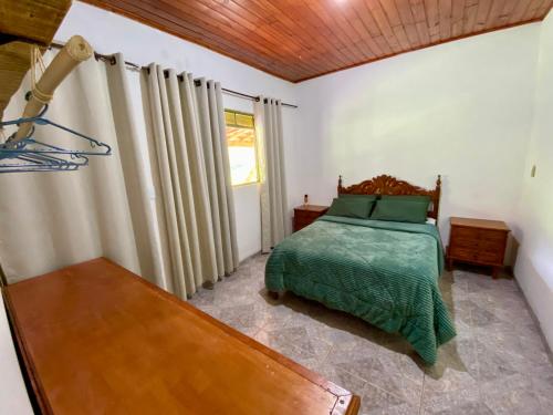 1 dormitorio con cama, mesa y ventana en Sitio Boa Esperança 20km de Monte Verde en Camanducaia