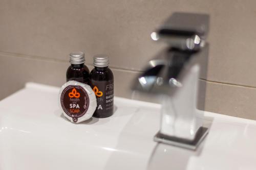 two bottles of syrup sitting on top of a sink at The Park Royal Collection in London