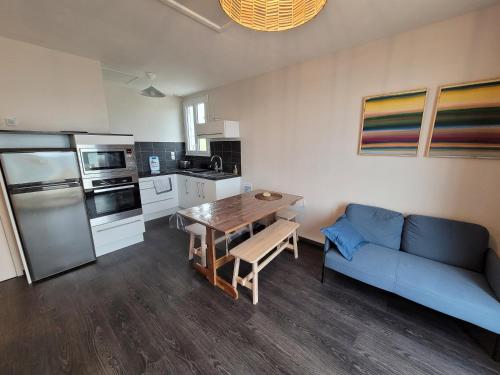 un salon avec un canapé bleu et une cuisine dans l'établissement Beach House - jusqu'à 5 personnes, à Plouescat