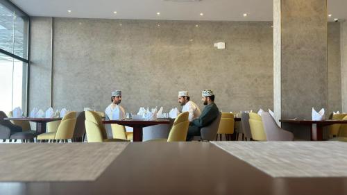 a group of men sitting at tables in a restaurant at Royal Plaza Hotel in Duqm