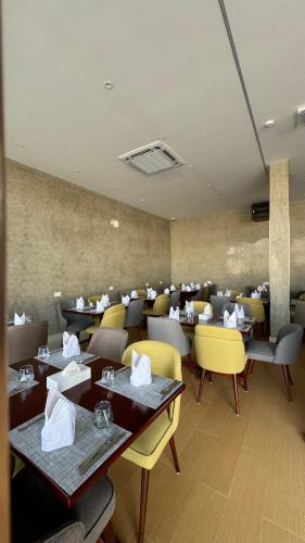a dining room with tables and yellow chairs at Royal Plaza Hotel in Duqm