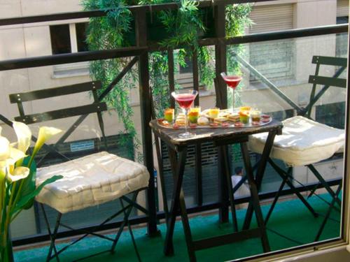 - une table et deux chaises sur un balcon avec boissons dans l'établissement Heart of Paris - Bastille & Marais Suite Deluxe, à Paris