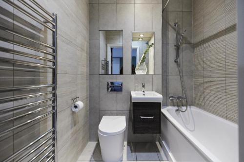 a bathroom with a toilet and a sink and a tub at The Wembley Crib - Lovely 1BDR Flat with Balcony in London
