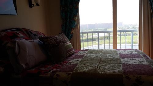 a bed with a quilt and a window with a view at Two Bedroom Apartment at Golf Porto Marina in El Alamein