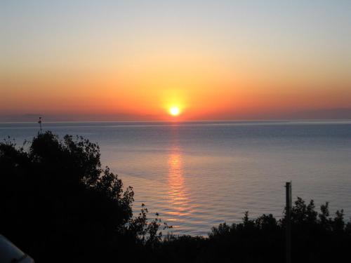a sunset over the water with the sun setting at Travlos Studios in Póros Kefalonias