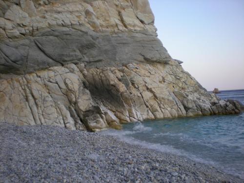 a rock cliff next to a beach with the water at ZACHAROULA ROOMS 2 in Manganítis
