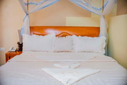 a white bed with a wooden headboard and white pillows at Tigers's apartment Hotel in Bujumbura