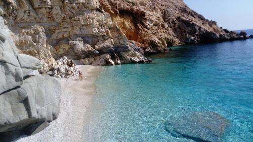 a beach next to a rocky cliff at ZACHAROULA ROOMS 2 in Manganítis