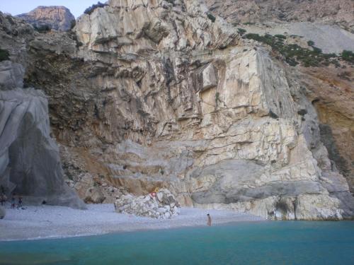 a rocky cliff with a beach next to the water at ZACHAROULA ROOMS 2 in Manganítis