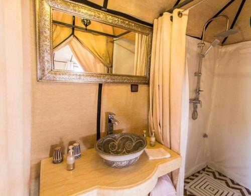 La salle de bains est pourvue d'un lavabo et d'un miroir sur un comptoir. dans l'établissement Merzouga Stars Luxury Camp, à Merzouga