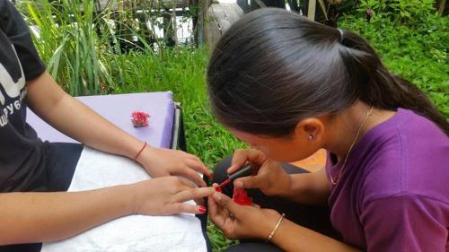 a young girl cutting a red object with scissors at Banteay Srey Women's Only Traditional Spa and Homestay in Kampot