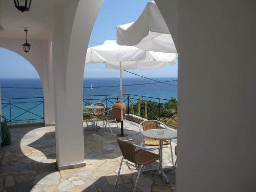 a patio with chairs and tables and an umbrella at Travlos Studios in Póros Kefalonias