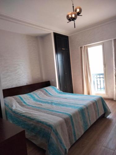 Schlafzimmer mit einem Bett und einem Fenster in der Unterkunft Appart vacances marina in Agadir