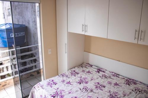 um pequeno quarto com uma cama com um cobertor florido em Otimo apto 9 min do aeroporto em Florianopolis SC em Florianópolis
