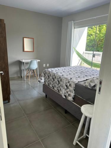 a bedroom with a bed and a table and a window at Residencial Valentina Jurere in Florianópolis