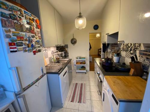 a kitchen with a white refrigerator and a sink at Appartement entier 3 pieces. in Argenteuil