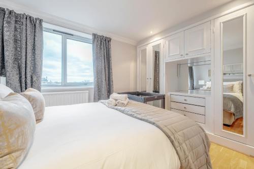 a white bedroom with a bed and a window at Stunning Flat on King's Road, Chelsea with Balcony in London