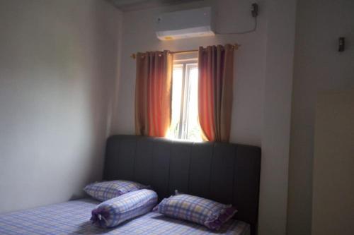 1 dormitorio con cama con almohadas y ventana en OYO 93457 White House Syariah, en Kubang