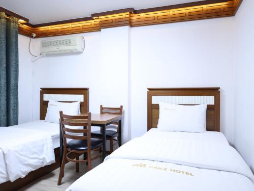 a room with two beds and a table and a desk at Goodstay Andong Park Hotel in Andong