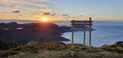 un cartello in cima a una collina con il tramonto di Koselig hus med fantastisk utsikt, Stadlandet a Stadlandet