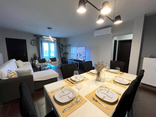 Infinity Horizon Syros Apartment في Lazaréta: غرفة طعام وغرفة معيشة مع طاولة وكراسي