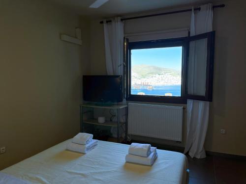 a bedroom with a bed and a window with a view at Infinity Horizon Syros Apartment in Lazaréta